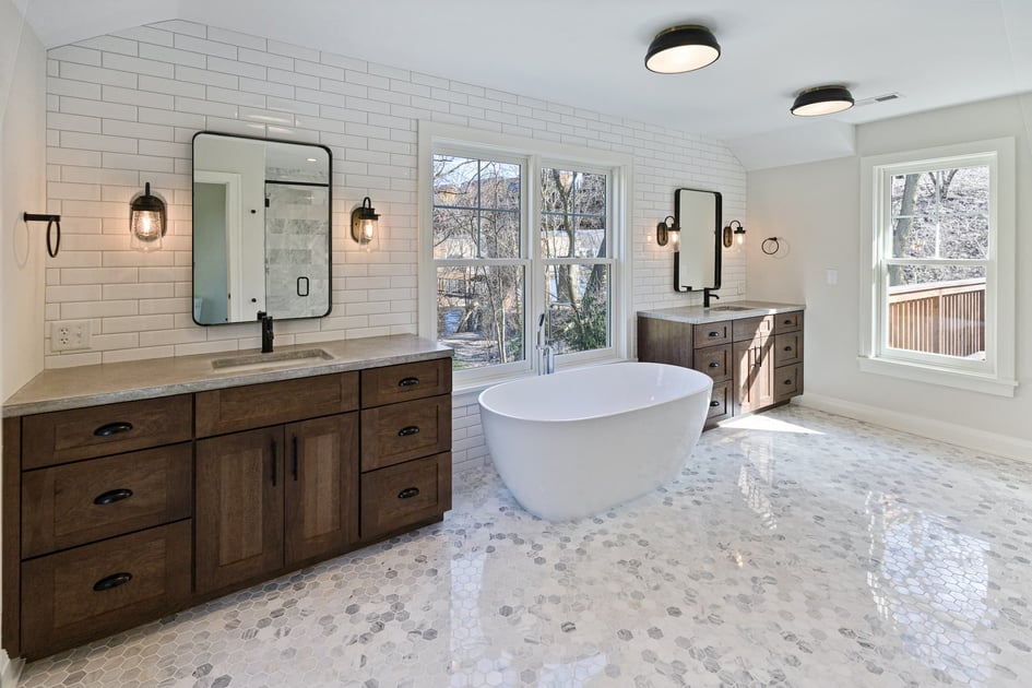 Freestanding bathtub and wooden cabinets in a bathroom by Hogan Design and Construction