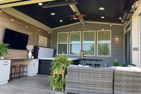 Outdoor porch with a wall mounted TV, ceiling fan, and hot tub with seasonal cover