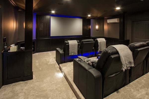 A luxurious home theatre with mood can lighting, leather recliners, and a retractable projector screen