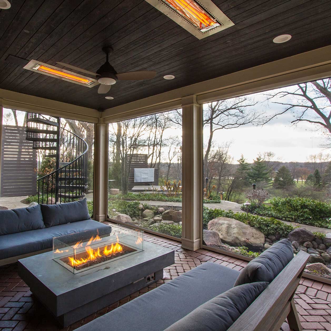 Luxurious screened in porch with a gas firepit built into a table and surrounded by outdoor sofas