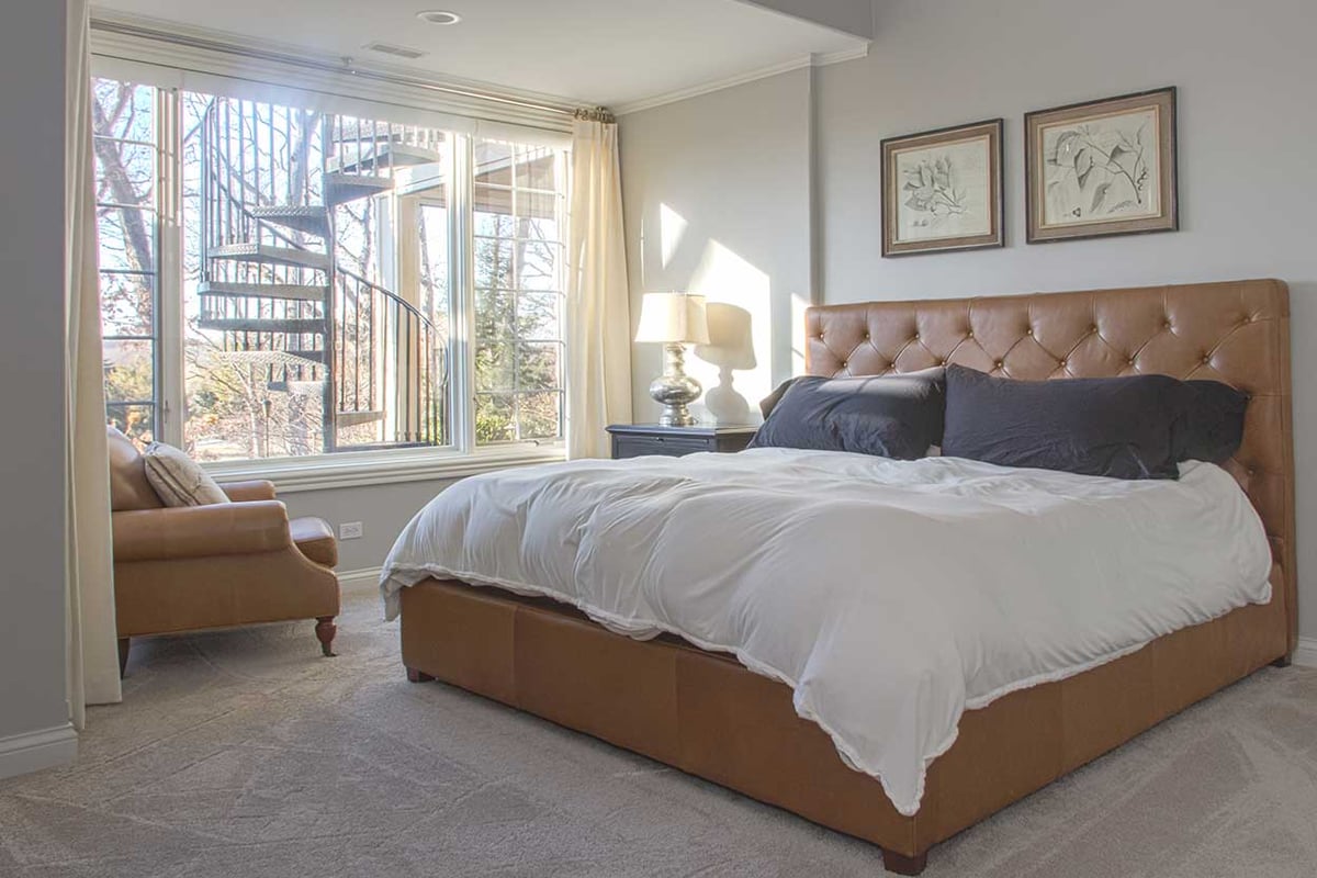 Basement bedroom with an almost ceiling-to-floor window allowing daylight in