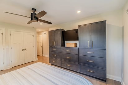 A functional and efficient storage system in a master suite with a large bed and a ceiling fan mounted above