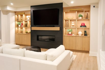 White sectional couch positioned in front of a wall mounted TV and an entertainment stand