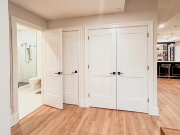 Simple, white, contemporary doors for added storage space in the basement remodel
