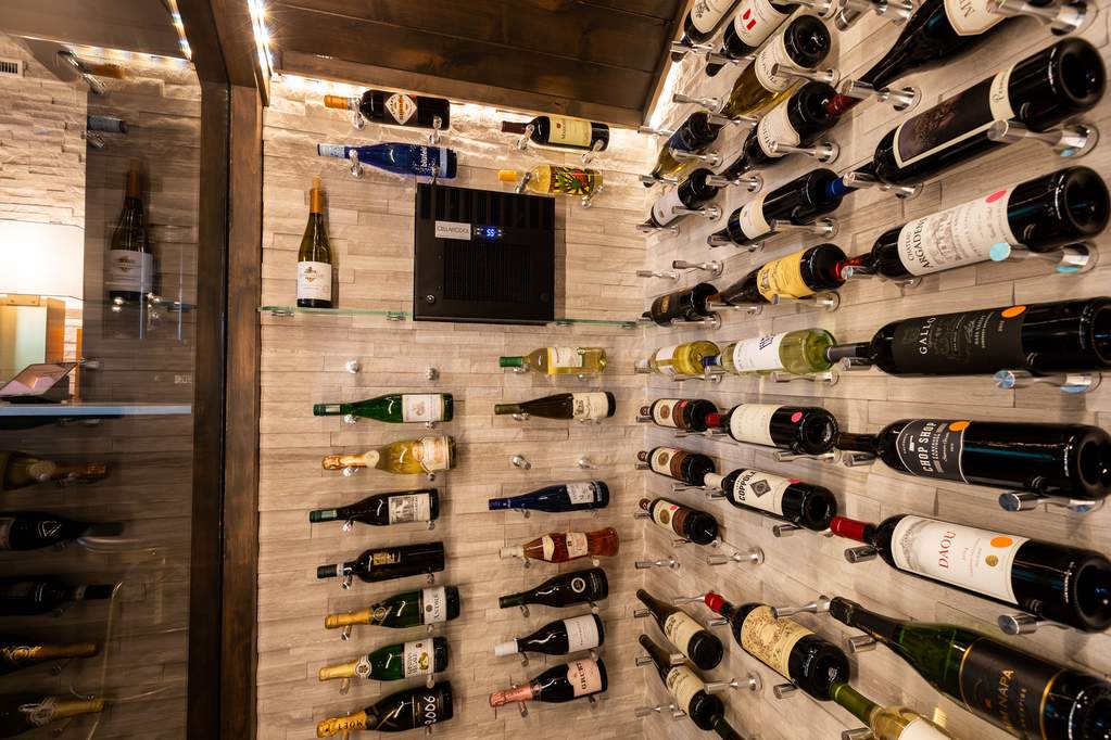 A converted under the stair closet to a temperature controlled wine cellar with a flagstone wall and wine display shelving