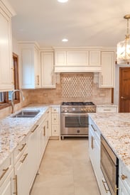 A spacious walkway between the kitchen counter and a kitchen island in a contemporary home remodel with white cabinetry and storage solutions.