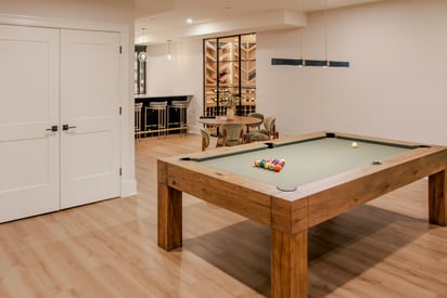 A pool table in the basement with large, wooden, decorative legs