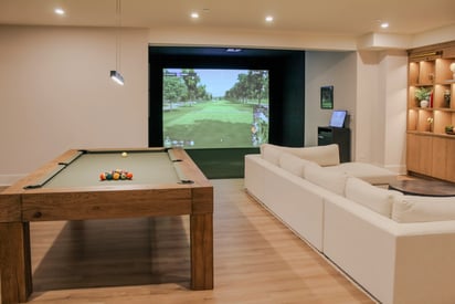A basement removed perfect for entertaining with a pool table, golf simulator, and large sectional couch