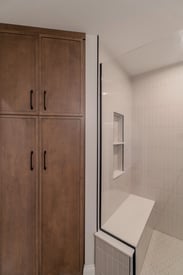 A spacious powder room with a walk in shower, a shower bench, and lots of storage space.