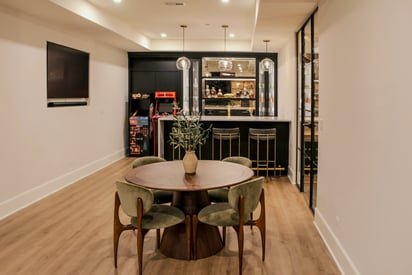 A four-seat table in the basement positioned in the middle of the room in front of a bar and wine storage room