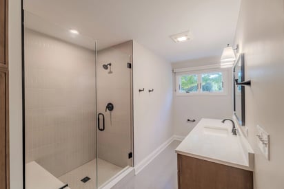 Luxurious powder room with a walk in shower, lots of natural light, and a single vanity for freshening up