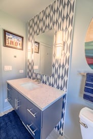 A single bathroom vanity with a decorative wall art pattern being the mirror and countertop