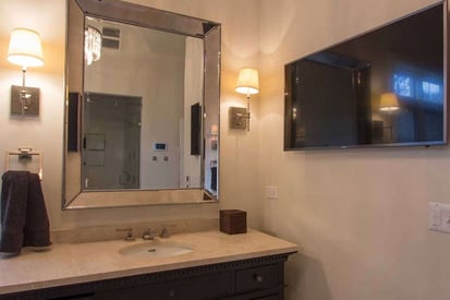 Wall mounted TV in a bathroom on the opposite side of the stand alone bathtub