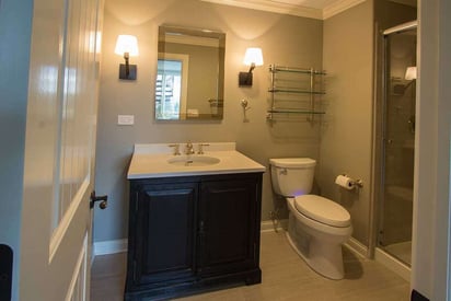 half bath with two lamps mounted on the sides of a single vanity mirror and a shower to the right of the entrance