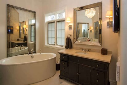 warm and inviting master bathroom with a stand alone tub and multiple mirrors