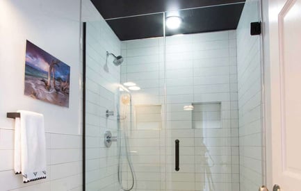 Bathroom shower door with a black ceiling, built in shelving, and a towel rack with a decorative towel outside