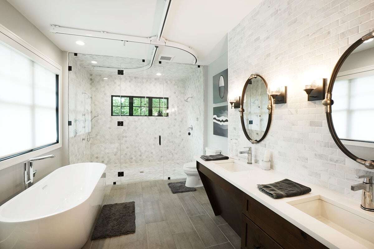 This curbless and frameless walk-in shower is complemented by an adjacent freestanding tub | Hogan Design and Construction