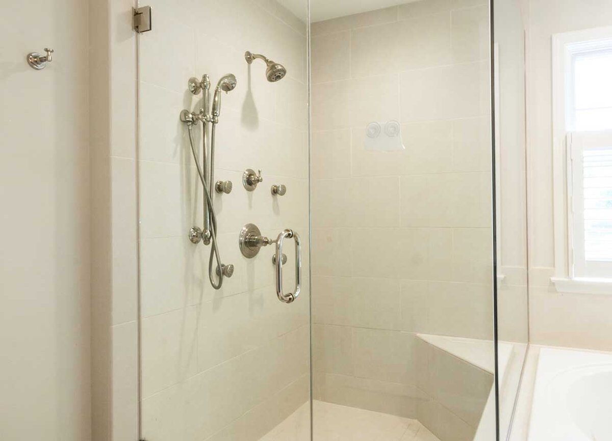 Wagner Master bath shower area in enclosed glass. Shower pieces contains stainless steel rain heads and knobs