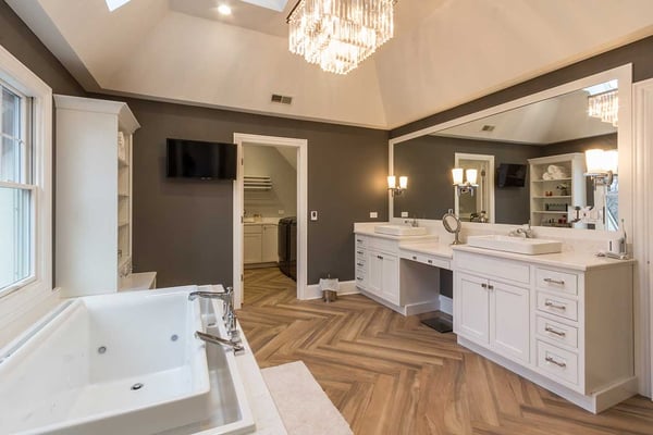 luxurious master bathroom with a walk-in closet, full wall mirror with a double vanity and patterned hardwood flooring