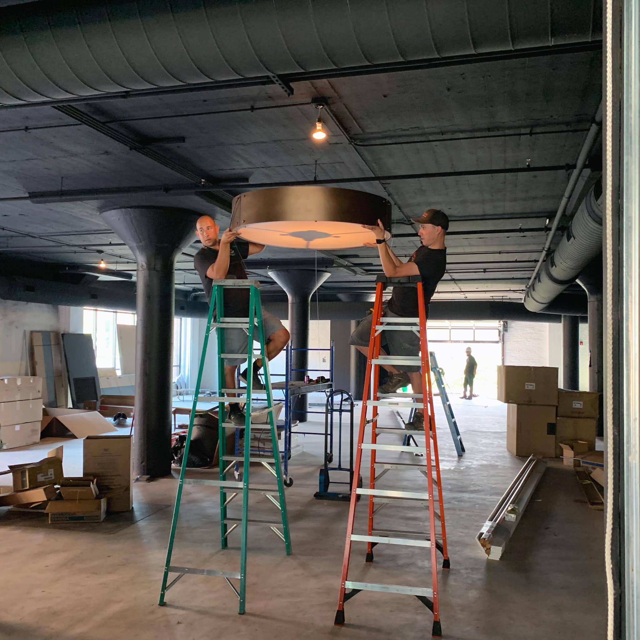 Hogan workers mount round lighting fixture in commercial project