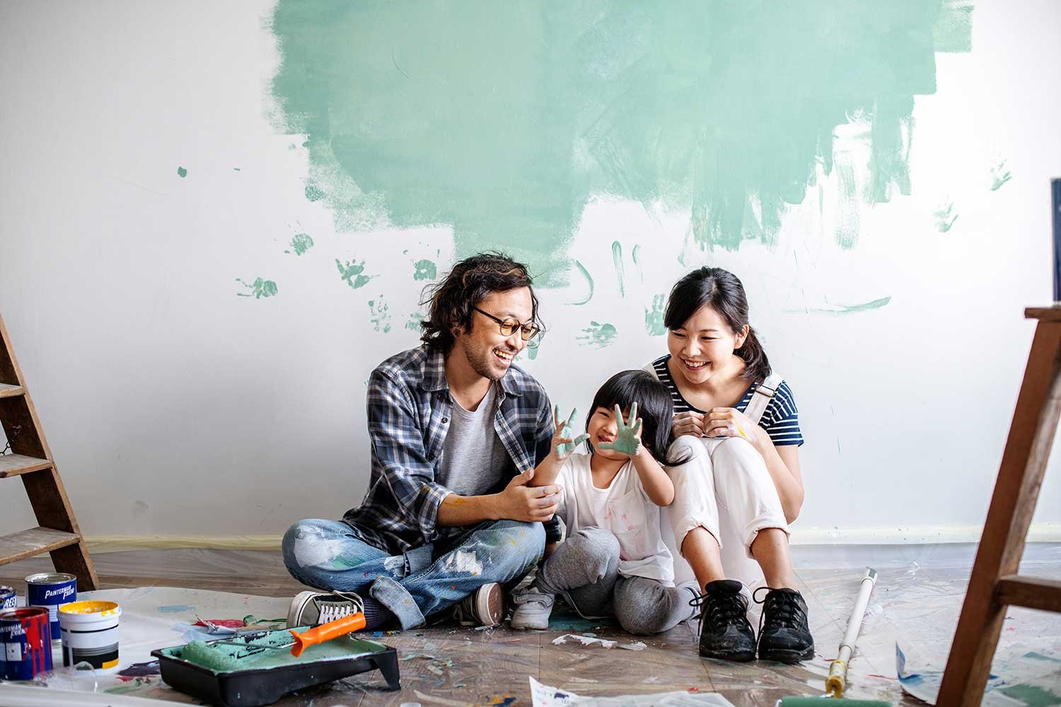 Two people sit on green and white wall picking colors