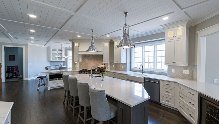 Luxurious kitchen with a white quartz countertop, 4 upholstered bar chairs and an ebony hard wood floor
