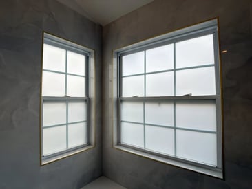 Two side by side windows in a master bathroom for natural light that are fogged out
