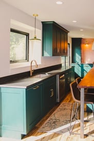 Decorative blue/green kitchen cabinets with soft, warm yellow lighting