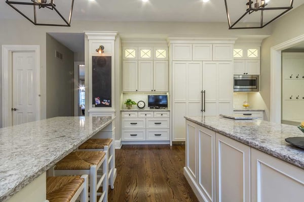 Luxurious and spacious kitchen remodel with a kitchen island for cooking and a separate kitchen island with white decorative stool seating. A butler's pantry can be seen in the background by white cabinets