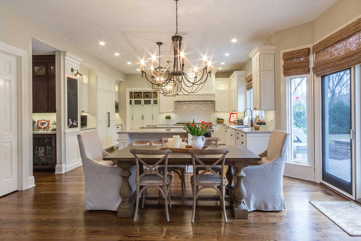 Dining table with bronze chandelier and white cabinets