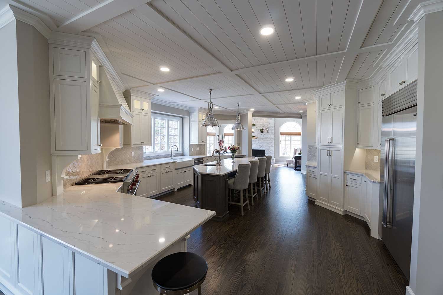 Beautiful and open pure white kitchen remodel with a very large kitchen counter, an island with bar stool seating, and a butler's pantry for more storage