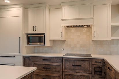 Kitchen stove with a hood mounted overhead and lots of white cabinetry for storage space
