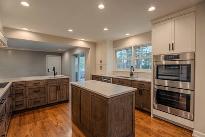 Wide angle of a home chef luxury kitchen with a kitchen island, stacked ovens, and multiple countertops