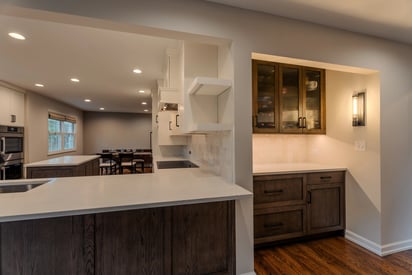 Side by side angle of a kitchen and butler's pantry, well lit from natural light and can lights