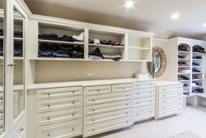 Large walk-in closet with ample drawers and shelves, featuring white cabinetry
