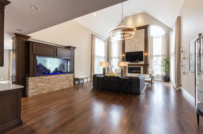 Living Room featuring wood floors, a fish tank, a fireplace with stone & wood accents and a large chandelier