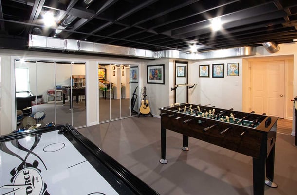 Warm and inviting basement with exposed rafters for a more rustic aesthetic. Great for entertaining with air hockey and foosball