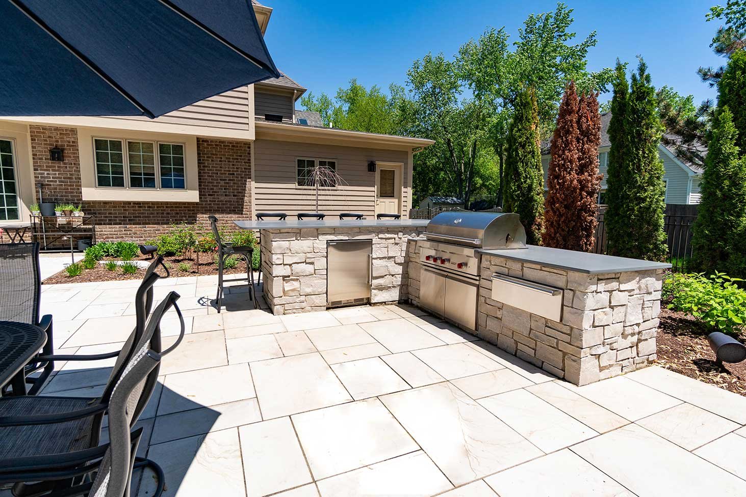 Outdoor kitchen with a prep station, stainless steel grill, pizza oven, and a mini fridge