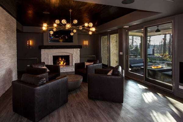 Warm and inviting basement seating area with four square arm chairs positioned infront of a fireplace and a sliding screen door