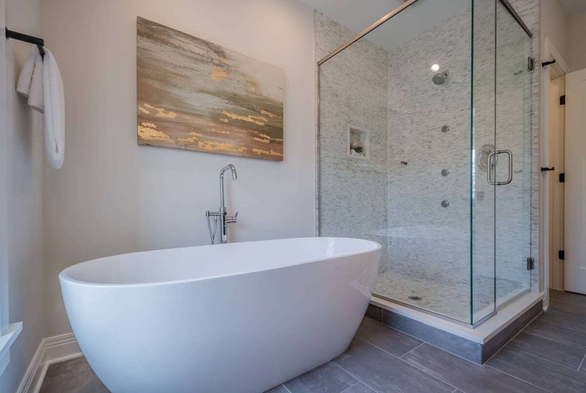 Bathroom with a white bathtub and an enclosed shower area with shower heads