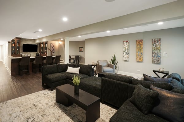 Luxury home basement remodel with vinyl flooring, a full wet bar, and a large U-shaped sectional couch