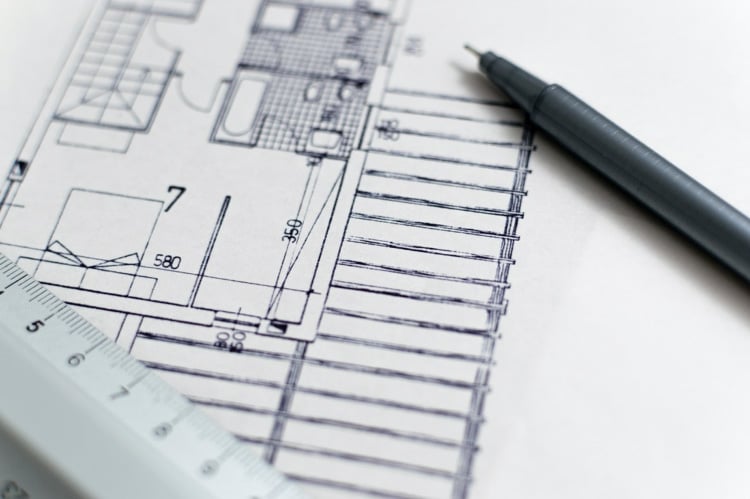 Architectural sketch of a home floor plan with a pen and a ruler laying on top