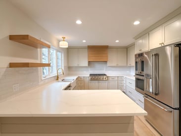 Quartz kitchen island with floating shelves mounted on the wall on the left with stainless steel luxury appliances on the right