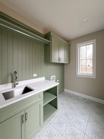 A sage and white laundry room/mudroom with cream walls
