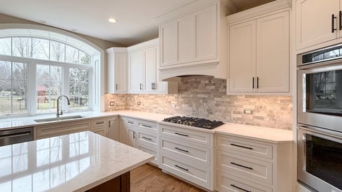 Wide angle photo of a kitchen remodeling project with white cabinetry, stainless steel appliances, and a kitchen island