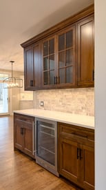 An elegant butler's pantry with a mini fridge, elegant backsplash, and plenty of storage space