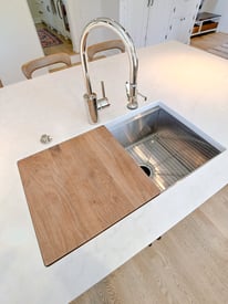 Close up photograph of a sink and basin mounted into the kitchen island with a prep station
