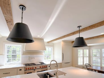 Close up of matte black pendant lights mounted above a kitchen island