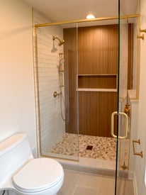Shower with a glass door open and an elegant built in shelf for added storage space
