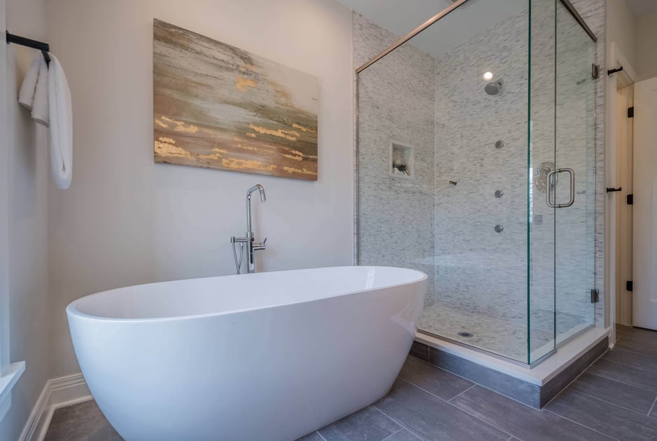 Bathroom with a white bathtub and an enclosed shower area with shower heads 